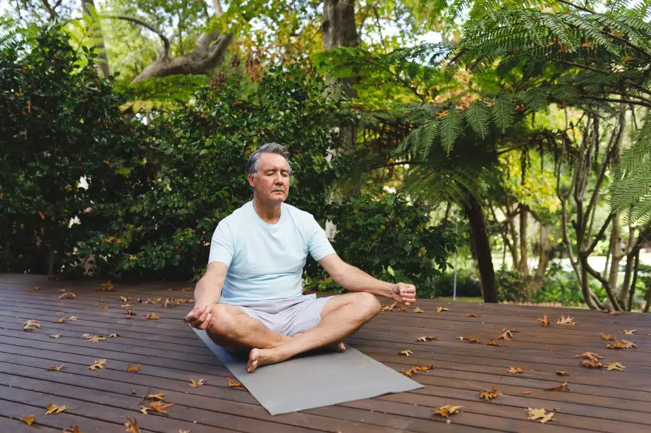 relaxed senior man practicing yoga therapy and meditating in the backyard