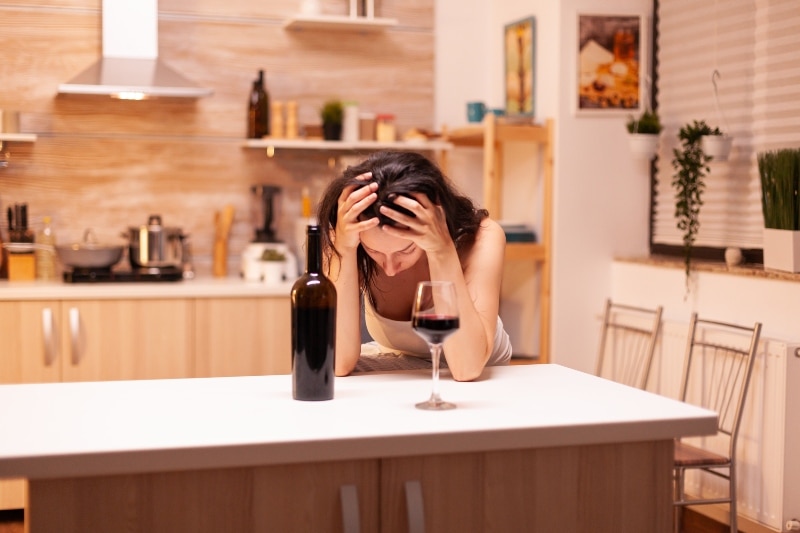woman with her head in her hands struggling with addiction and looking for alcohol rehab san diego